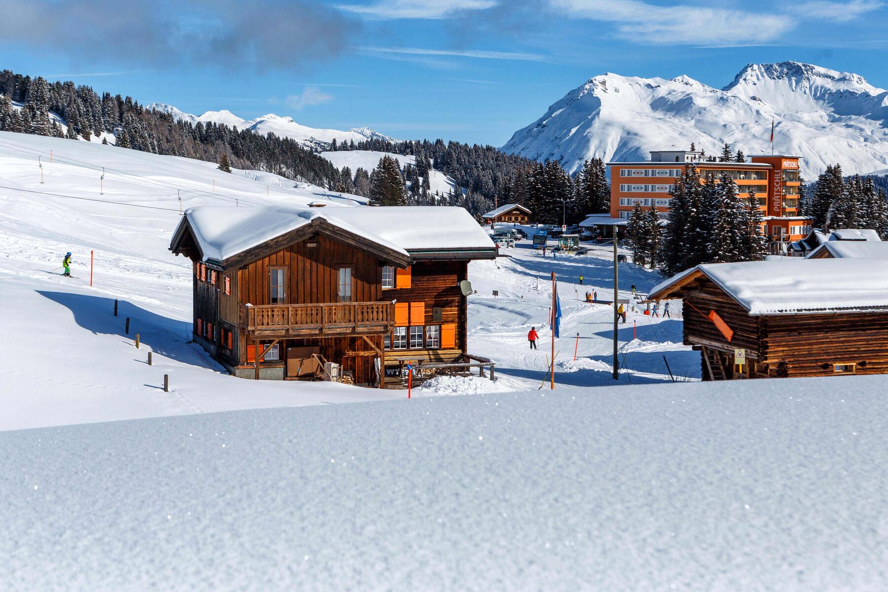 Die Fassade mit den orangen Läden, im Schnee