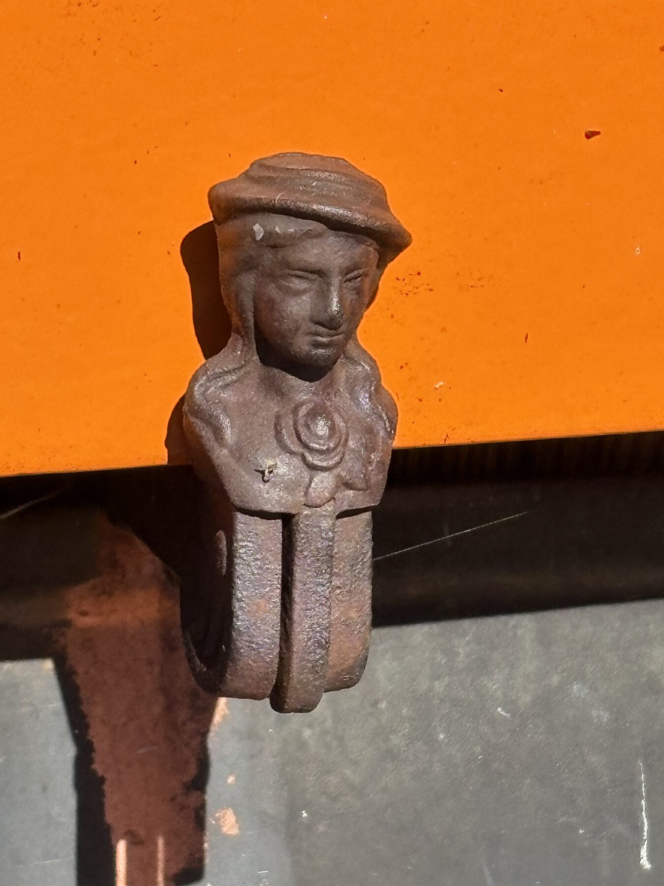 Der gusseiserne Ladenhalter vor dem orangen Fensterladen