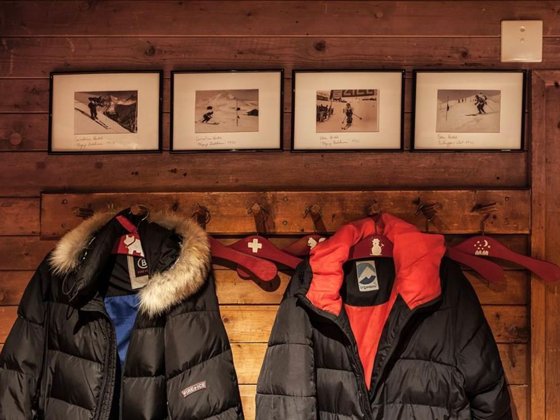 Die Garderobe mit Daunenjacken, darüber Fotos vom Skitraining